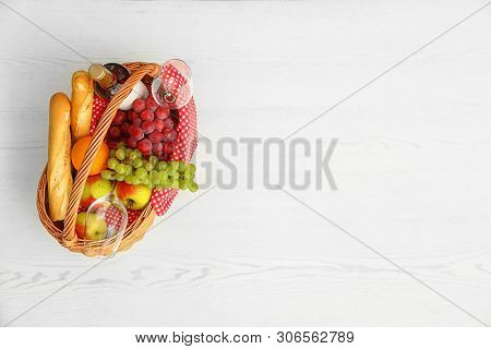 Picnic Basket With Products And Wine On White Wooden Table, Top View. Space For Text