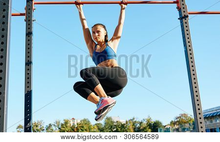 Fit Young Female Doing Pull Ups Exercises On Crossbar Outdoors. Athlete Woman Training Hard On The B