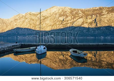 Autumn. Fishing Boats On The Water In A Small Harbor. Blue Sky And Mountains Reflected In The Sea. M