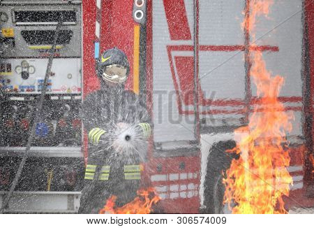Firefighter With Helmet And Uniform In Action And Flames Of Fire