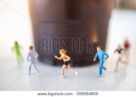 Food And Sport Concept. Close Up Of Group Of Runner Miniature Figure Running Around Plastic Cup Of I