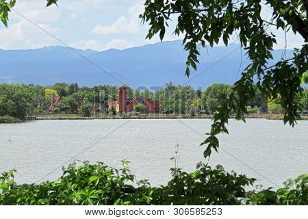 View Of Lake Rhoda In Denver, Colorado With Houses And Distance Mountains