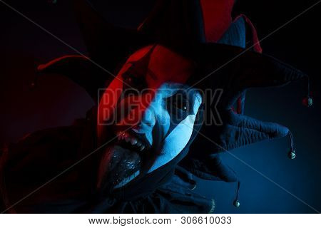 Spooky Screaming Jester With Black Eyes And Fangs Putting Out Tongue, Close-up.