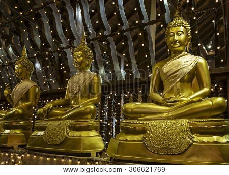 Row Of Three Golden Buddha Statues Sitting On Pillows In Seema Malaka Temple.