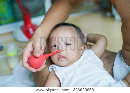 Father Using Baby Nasal Aspirator Mucus Nose Suction