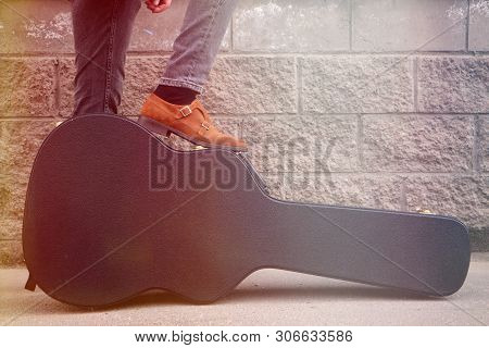 Man Put His Foot On A Hard Guitar Case. Hard Case For Electric Guitar. Man Dressed In Jeans Holding 