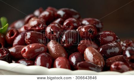 Pitted Kalamata Olives In Bowl On Rustic Wooden Background