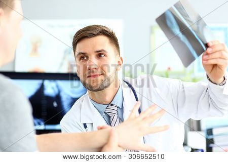 Portrait Of Smiling Doctor Talking With Patient About Good Snapshot Results. Doc Looking At Visitor 