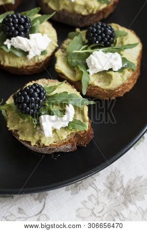 A Gourmet Lunch: A Plate Of Guacamole Sandwiches With Cream Cheese, Blackberries And Aragula On A De