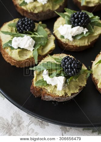 A Gourmet Lunch: A Plate Of Guacamole Sandwiches With Cream Cheese, Blackberries And Aragula On A De