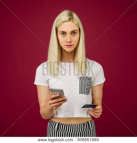 A Young Woman Holds A Smartphone And A Credit Card In Her Hands. Problems With A Bank Card, Because 