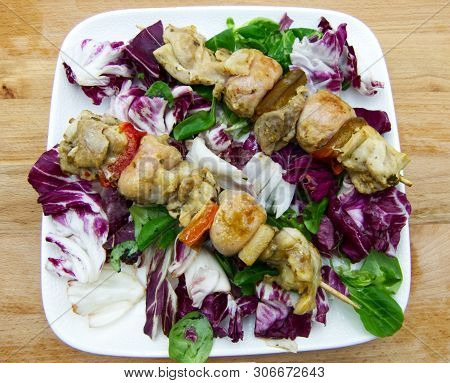 Chicken Skewers With Lettuce And Chicory On A White Plate, Wooden Table