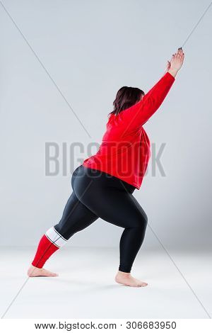 Plus Size Model In Sportswear, Fat Woman Doing Workout On Gray Background, Healthy Lifestyle Concept