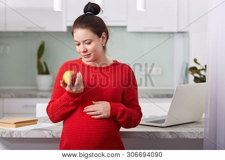 Pregnant Beautiful Girl Holding Apple In Hand. Attractive Future Mother Feels Relaxed And Happy, Cha