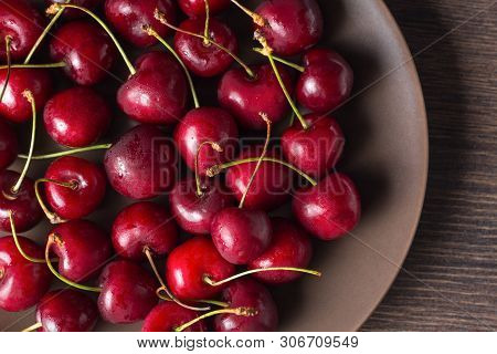 Red Cherries On A Brown Plate On A Wooden Table. Summer Food, Healthy Eating. Organic, Vegetarian, V