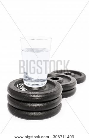 Glass Of Water Put On A Podium Of Weight Plates, Isolated On White Background.