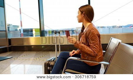 Beautiful Young Woman Looking Out Window While Waiting Boarding On Aircraft With Passport In Her Han