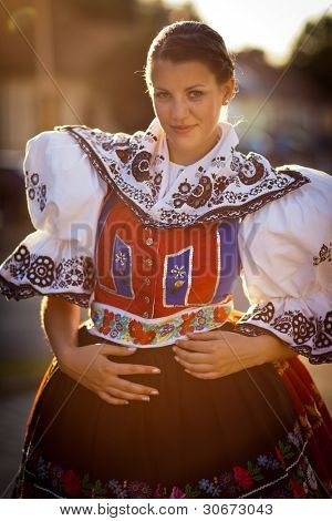 Hagyomány életben tartása: fiatal nő egy gazdagon díszített ünnepi ruha/regionális népviseletben (K