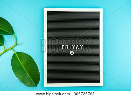 The Word Friday On A Letter Board With Happy Smiley Emoji Against Blue Background