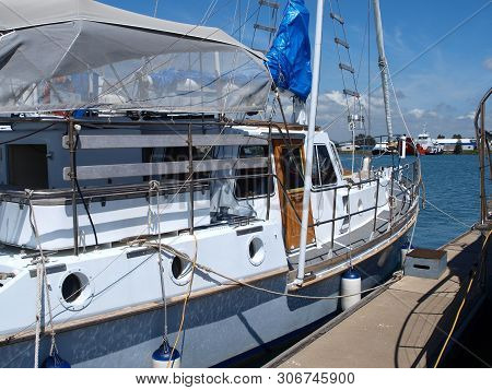 Gladstone Marina. Sailboat Tied Up To A Marina Floating Walkway In Tropical Water With Blue Sky Back