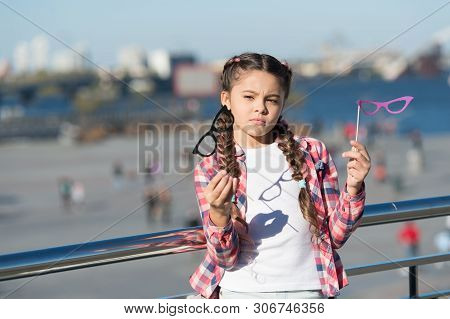 Which Props To Choose. Doubting Small Girl Choosing Glasses Props. Adorable Little Child Holding Pho