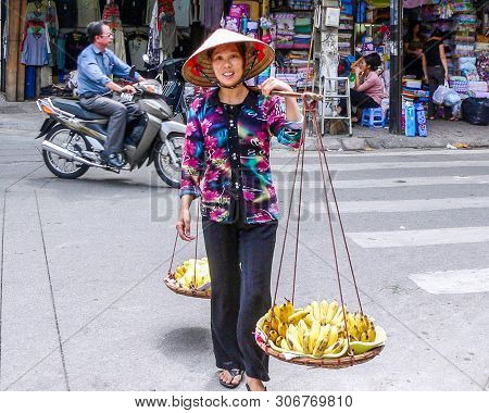 Hanoi, Vietnam - October 12th 2006: Woman Vendor Carrying And Selling Bananas. There Are Many Mobile
