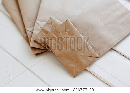 Paper Bags On Light Wooden Floor. Simple Brown Paper Bags For Lunch Or Meal. The Layout For The Desi