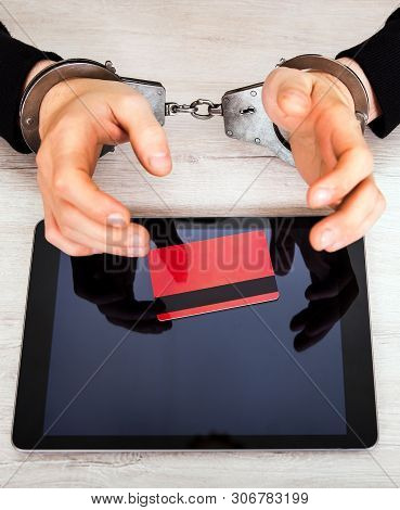 Person In A Handcuffs With A Tablet Computer And A Bank Card On The Table Closeup