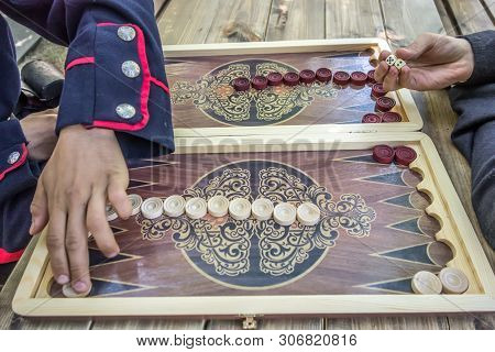Man's Hand Dropping Dice, While Another Man Moves A Pool In A Backgammon Game