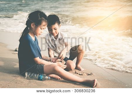 Two Asian Kids Is Helping Up Cleaning The Enviroment On The Beach