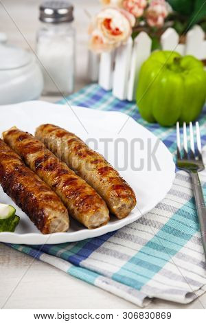 Kupaty In A White Plate And Vegetables On A Wooden Table. Sausages Grill. Tasty Food.