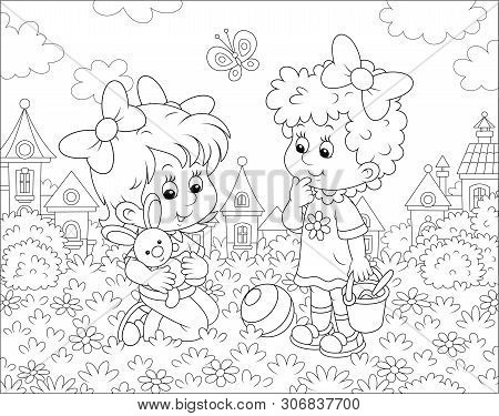 Cute Little Girls Playing With A Small Toy Rabbit Among Flowers On Grass Of A Lawn Against A Backgro
