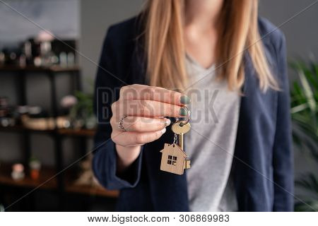 Concept Of Renting An Apartment. House Key In Womans Hands. Young Woman. Modern Light Lobby Interior