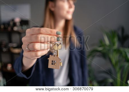 In The Foreground House Key In Womans Hands. Young Pretty Woman. Modern Light Lobby Interior. Real E
