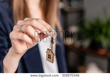 Concept Of Renting An Apartment. House Key In Womans Hands. Young Woman. Modern Light Lobby Interior