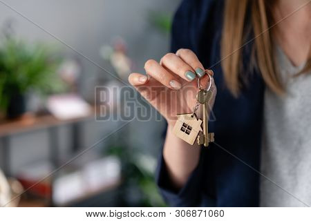 Concept Of Renting An Apartment. House Key In Womans Hands. Young Woman. Modern Light Lobby Interior