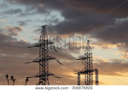 Silhouettes Of High Voltage Power Line Supports With Electrical Wires On Background Of Evening Sky W