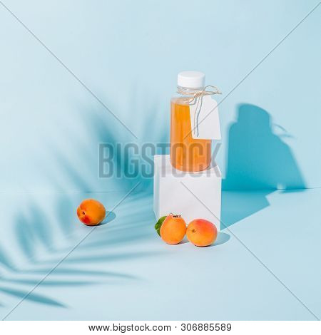 Peach Juice In A Bottle On White Paper Pedestal And Fresh Apricots At Foundation Casting Beautiful S