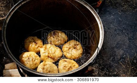 Cooking A National Russian, Bashkir, Tatar Dish - Belyashes In Nature, In A Cauldron On An Open Fire