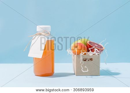 Peach Juice In A Bottle And Fresh Apricot, Apple And Blood Orange Resting In Disposable, Compostable