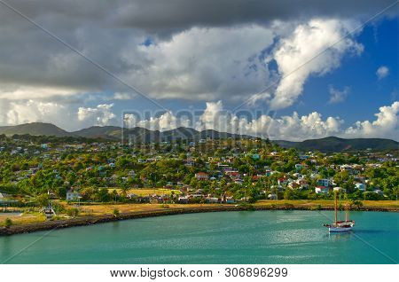 Bright Panoramic Image Of A Single Sailboat Moored In St John`s Harbour, Antigua With Colourful Cari