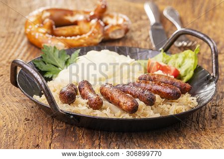 Nuremberg Sausages With Sauerkraut On Dark Wood