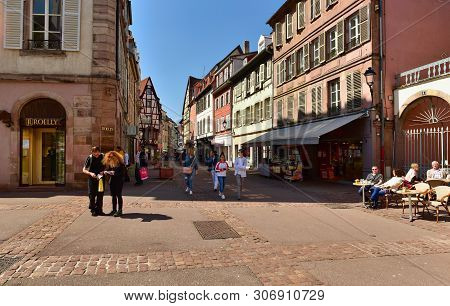 Colmar, France - April 18, 2019. People Walking Along The Old Street With Traditional Medieval House