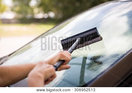 A Girl With A Brush In Her Hands Washes The Windshield Of The Car From A Large Number Of Dead Insect