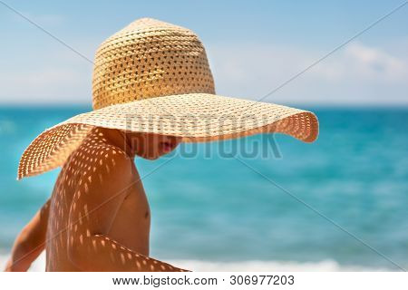 Cute Boy In A Straw Hat On The Beach