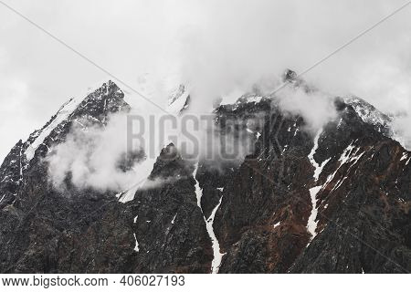 Atmospheric Minimalist Alpine Landscape With Hanging Glacier On Snowy Rocky Mountain Peak. Low Cloud