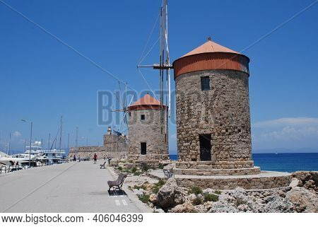 RHODES, GREECE - JUNE 9, 2019: The medieval stone windmills at Mandraki harbour in the Old Town of the Greek island of Rhodes.