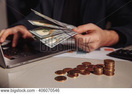 Man With Dollar Banknotes In His Hand Working Using Laptop. Investment And Business Concept