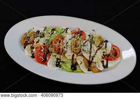Heirloom Tomatoes And Mozzarella Salad In A White Plater With Black Background