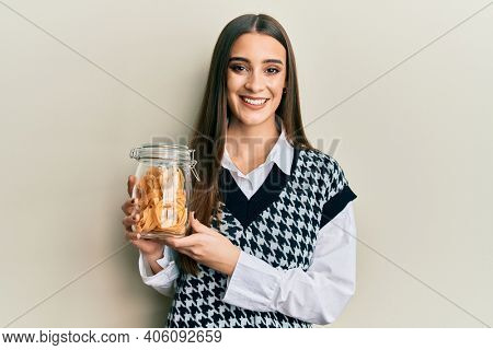 Beautiful brunette young woman holding jar with spaghetti pasta looking positive and happy standing and smiling with a confident smile showing teeth 